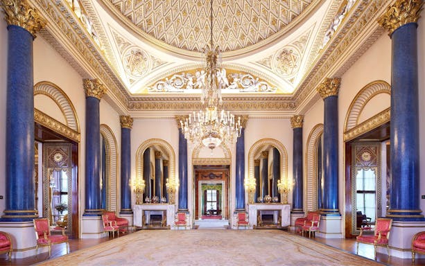 Buckingham Palace State Room with ornate ceiling, chandeliers, and blue columns.