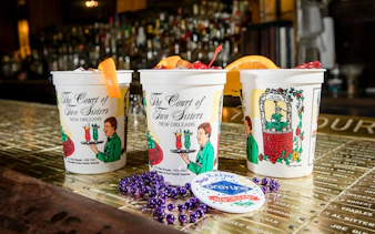 Court of Two Sisters cups with cocktails on a bar, New Orleans Craft Cocktail Walking Tour.