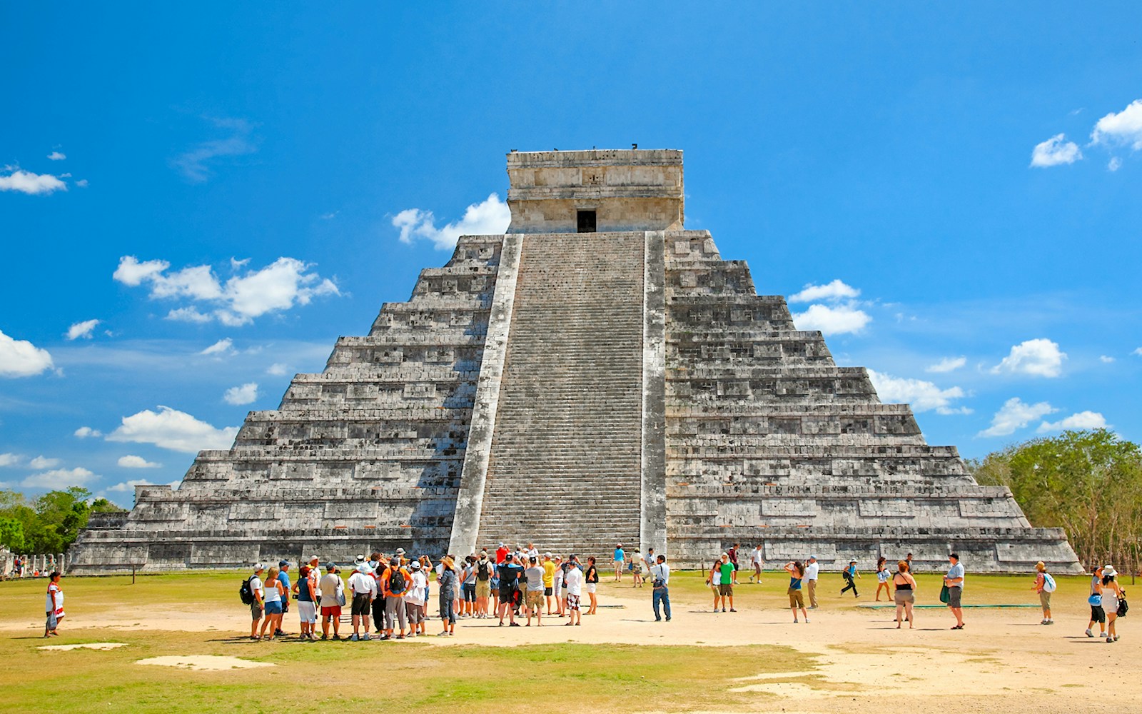 Chichen Itza's El Castillo pyramid in Yucatán, Mexico, with tourists exploring the ancient Mayan site.