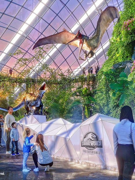 People exploring dinosaur exhibits at Jurassic World in Gardens by the Bay.