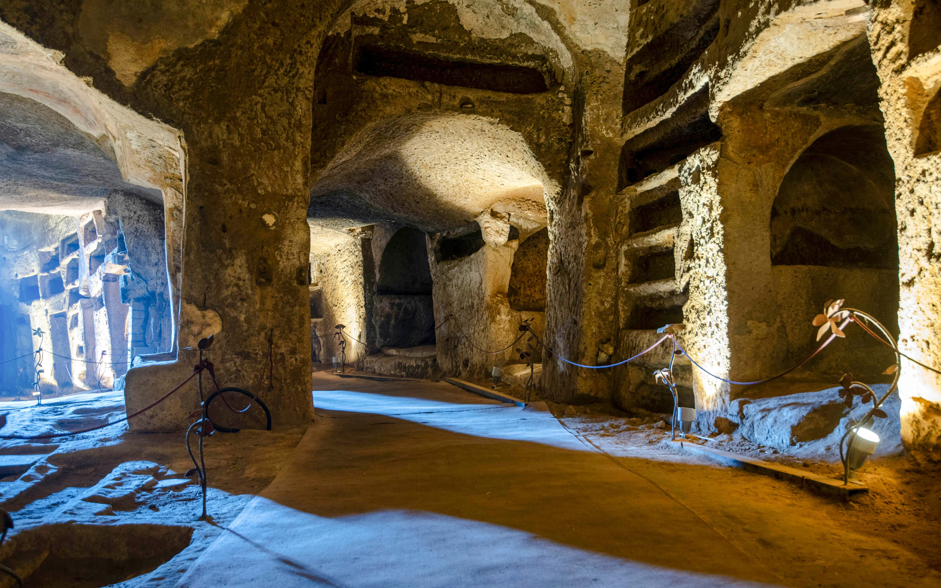 Catacombs of San Gennaro with ancient burial niches and illuminated pathways.