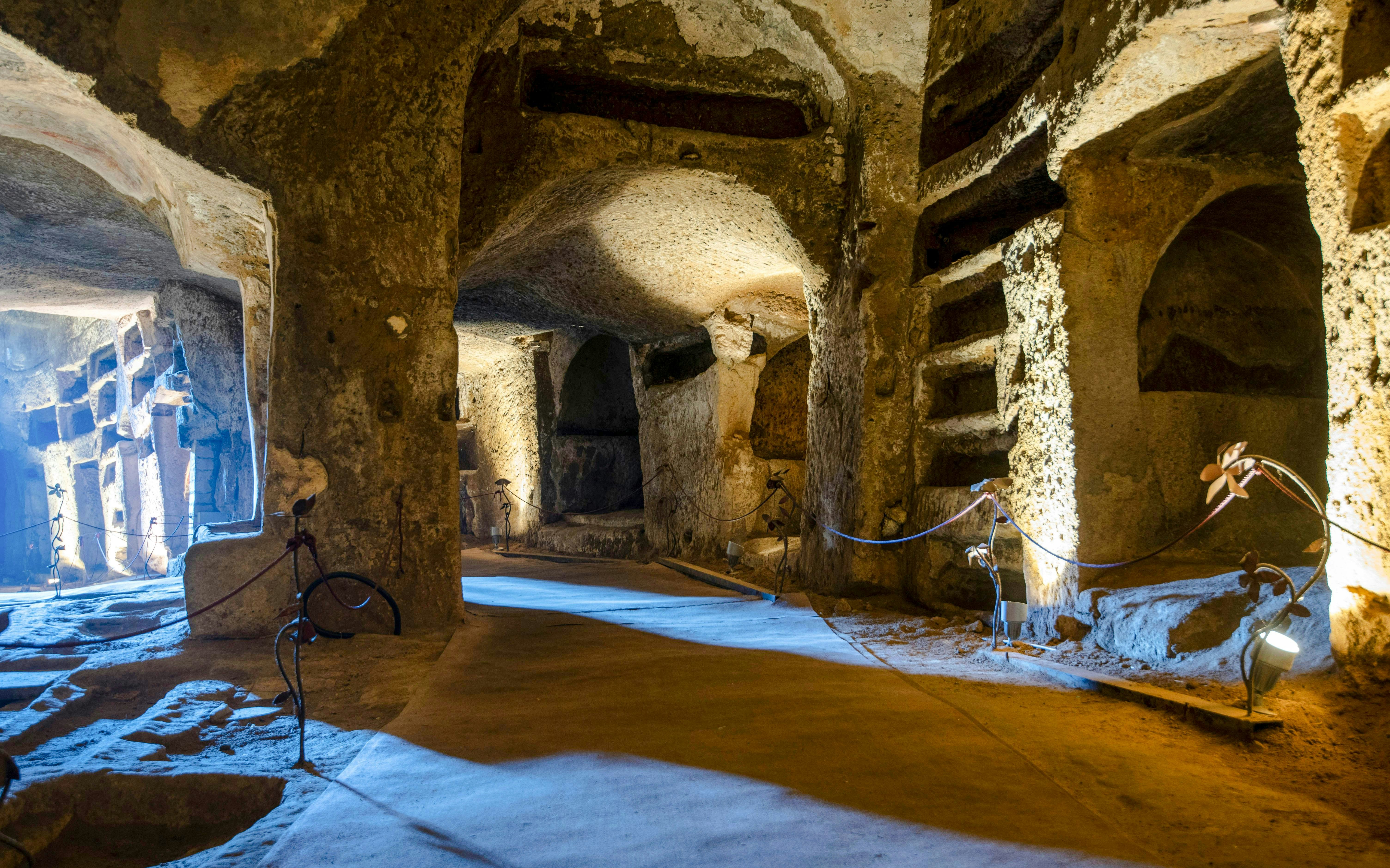 Catacombs of San Gennaro with ancient burial niches and illuminated pathways.