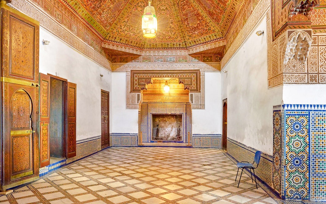 Ornate interior of Bahia Palace in Marrakech, Morocco, featuring intricate tilework and carved wooden doors.
