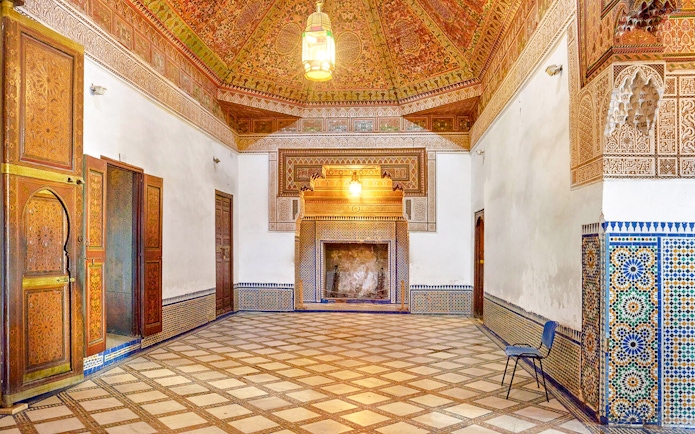 Ornate interior of Bahia Palace in Marrakech, Morocco, featuring intricate tilework and carved wooden doors.