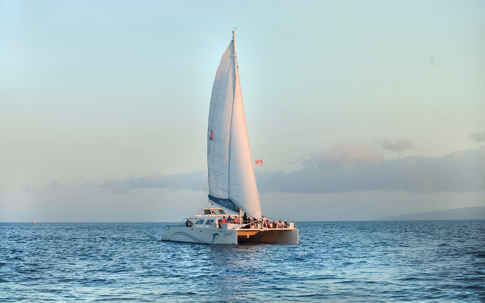Catamaran sailing at sunset during whale watching tour in Maui, Hawaii.