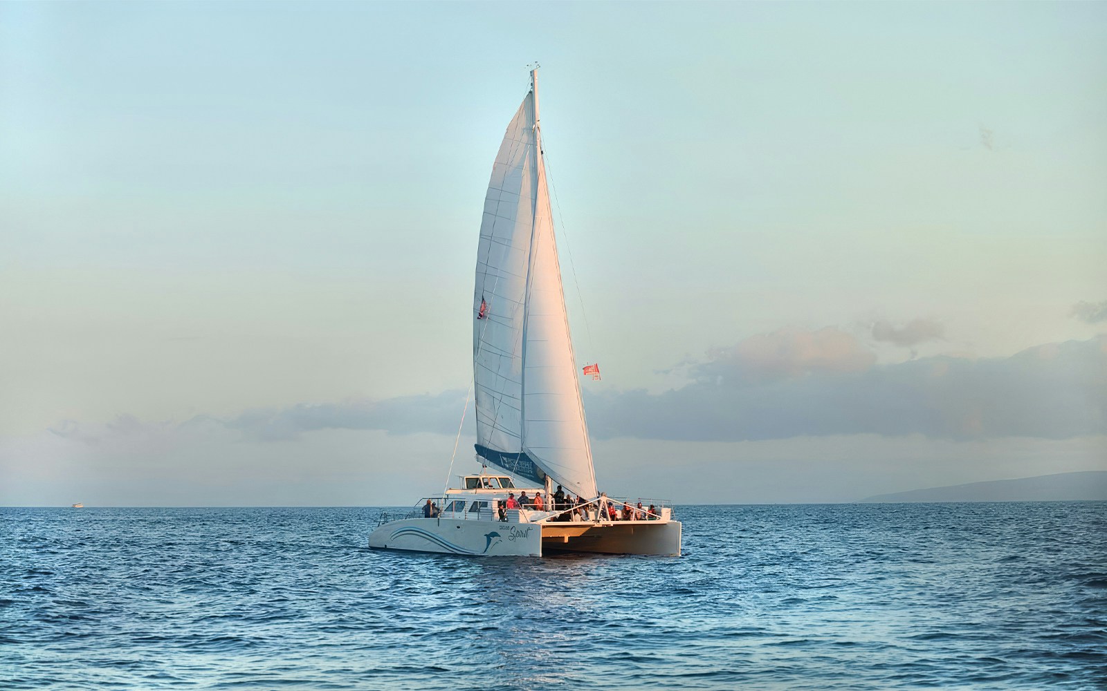 Catamaran sailing at sunset during whale watching tour in Maui, Hawaii.