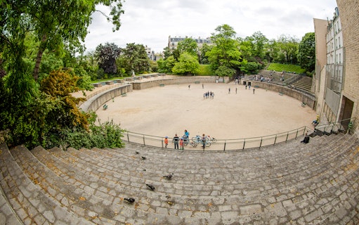 Arenes de Lutece amphitheater in Paris, France, with visitors exploring the historic site.