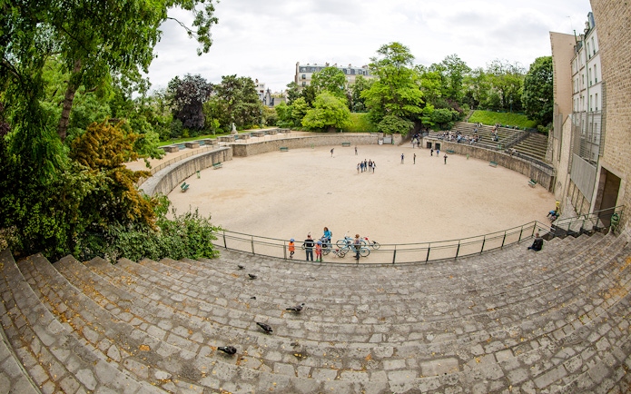 Arenes de Lutece amphitheater in Paris, France, with visitors exploring the historic site.