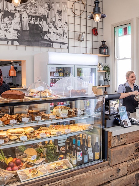 Cafe interior with pastries and drinks, barista serving a customer, part of Mary Valley Rattler Train Experience from Gympie.