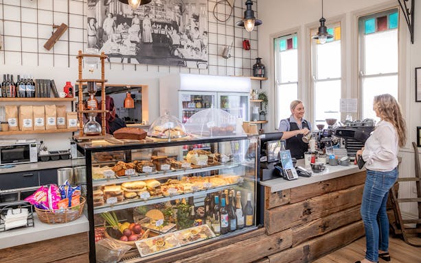 Cafe interior with pastries and drinks, barista serving a customer, part of Mary Valley Rattler Train Experience from Gympie.