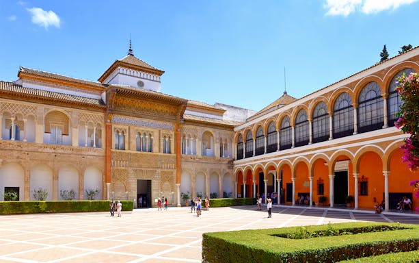 Royal Alcazar of Seville courtyard with visitors exploring historic architecture.