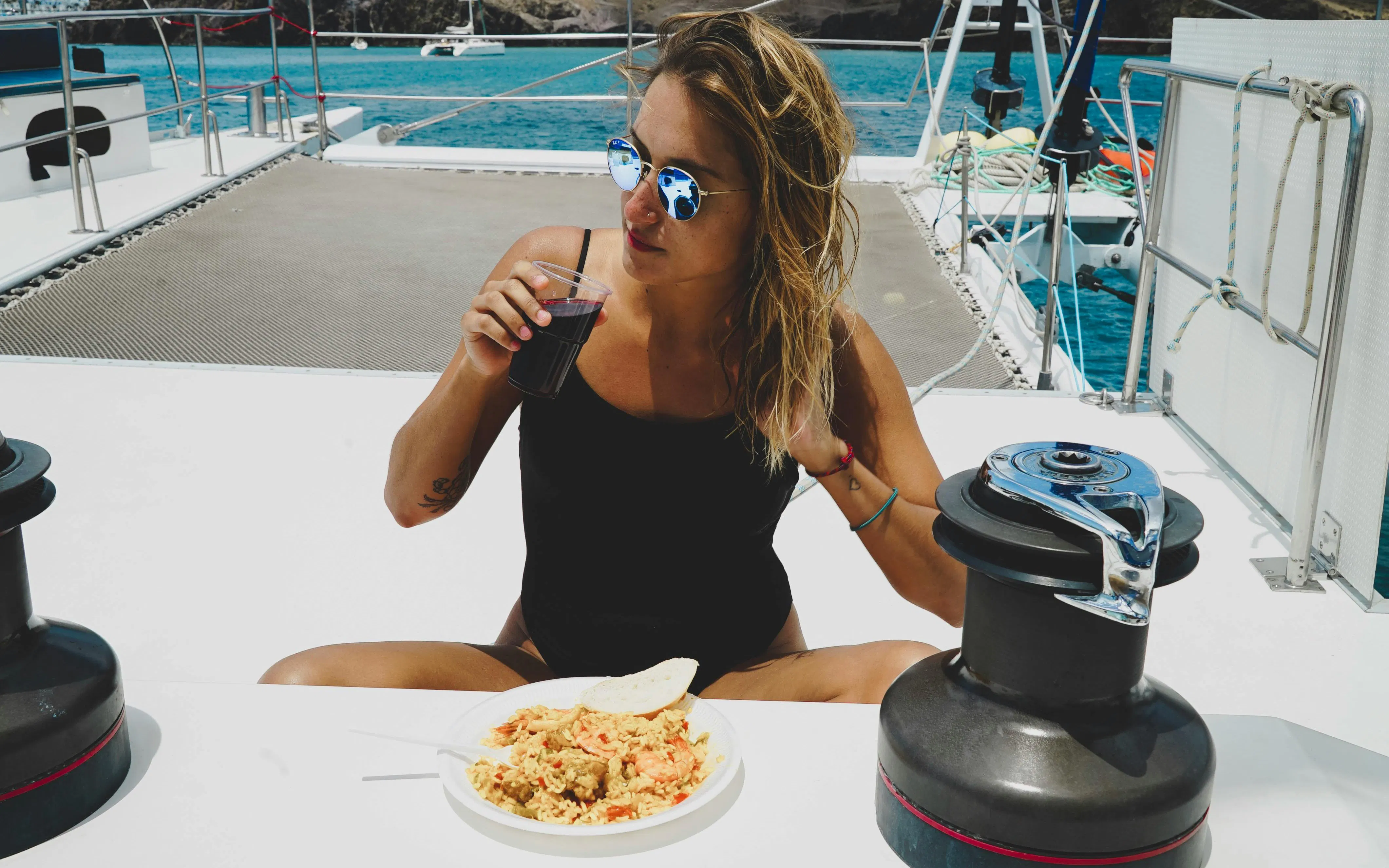 Woman enjoying a meal and drink on a boat during Lanzarote day trip to Papagayo Beaches.