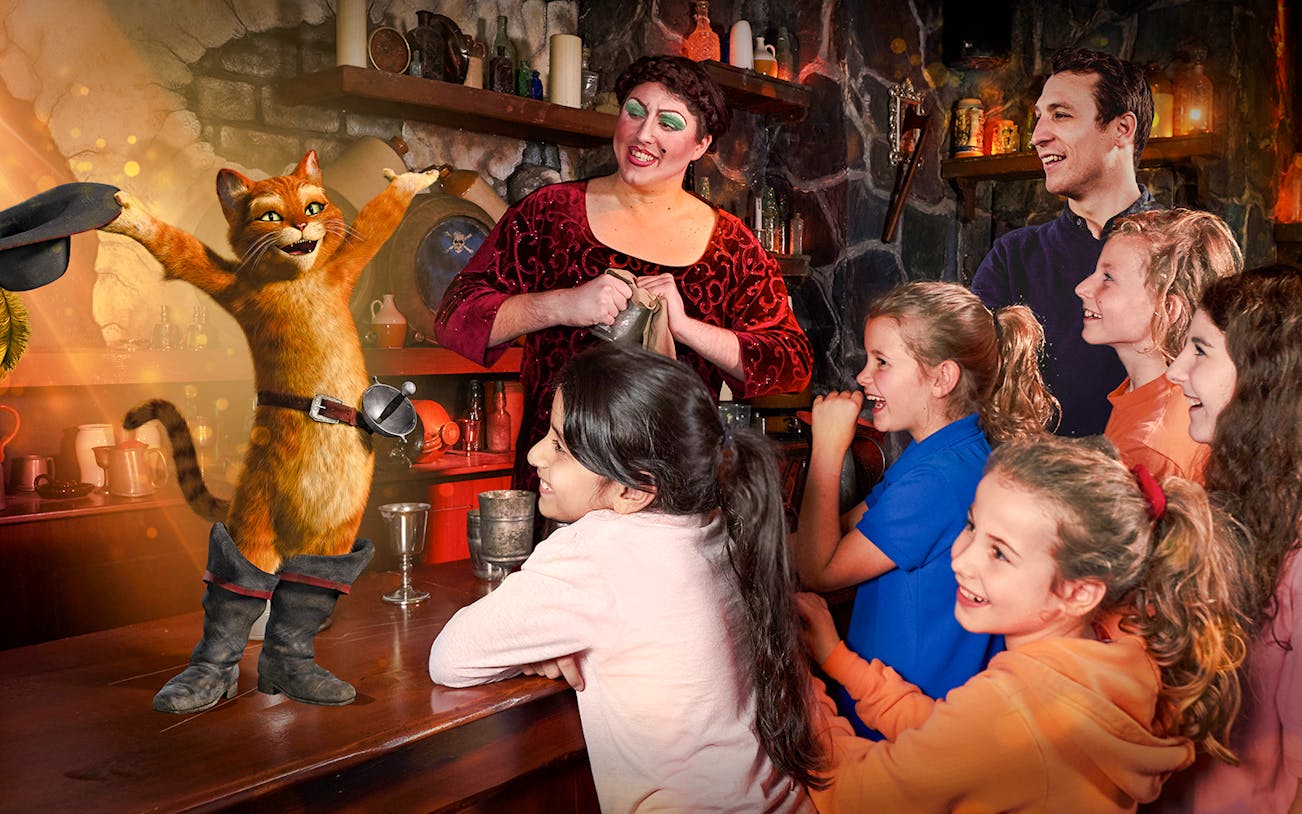 Guests interacting with Puss in Boots at Shrek's Adventure in London.