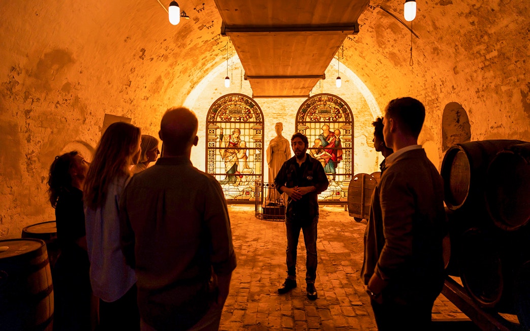 Tour group inside Carlsberg cellar with stained glass and statue exhibit.