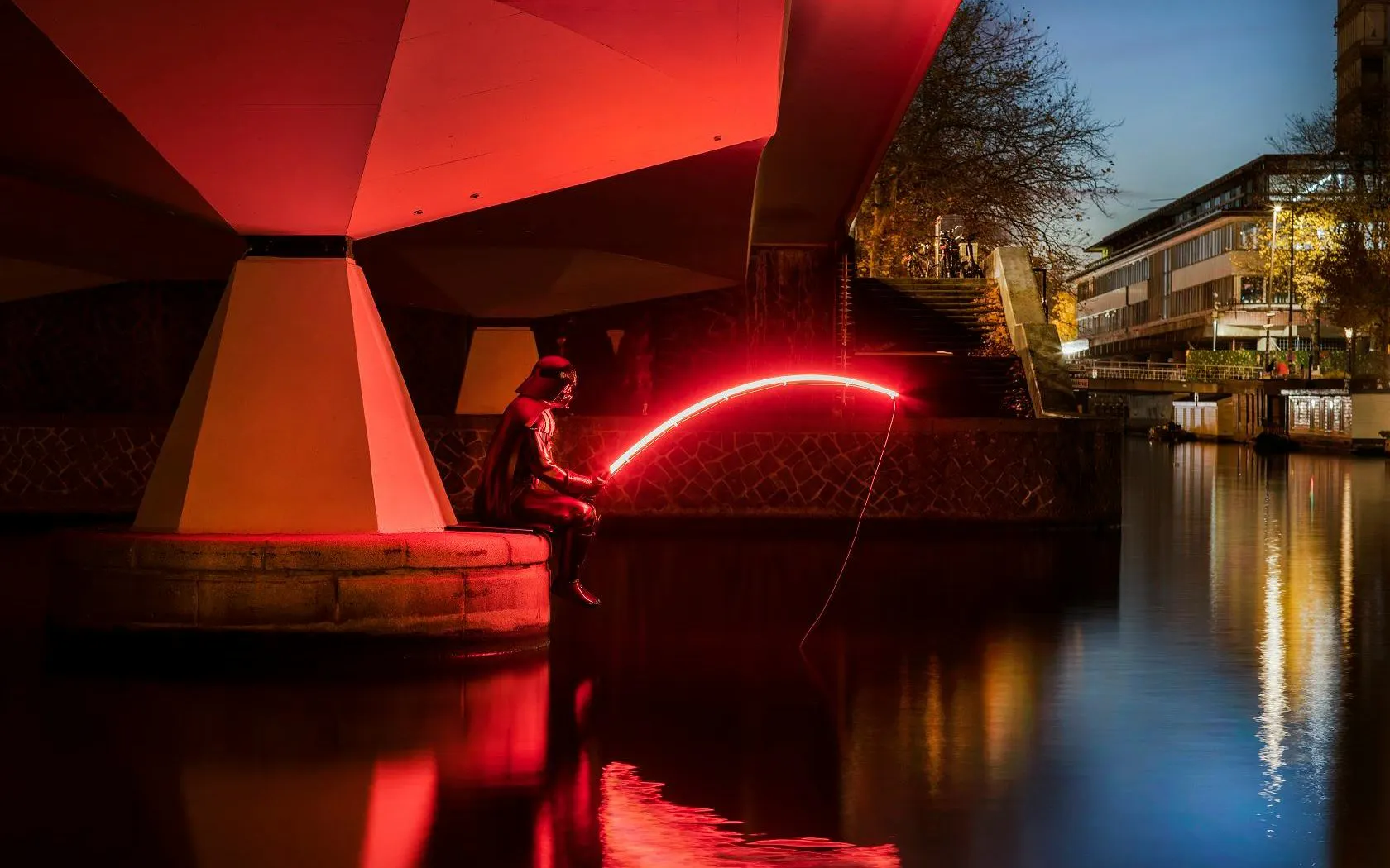 Person with glowing rod at Amsterdam Light Festival canal installation.