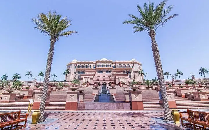 Emirates Palace in Abu Dhabi with palm trees and grand staircase, part of city tour from Dubai.