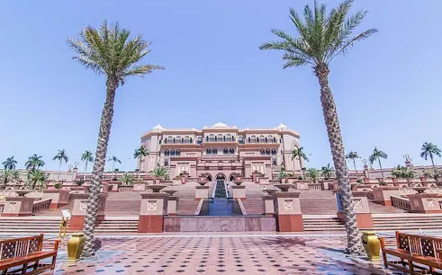 Emirates Palace in Abu Dhabi with palm trees and grand staircase, part of city tour from Dubai.