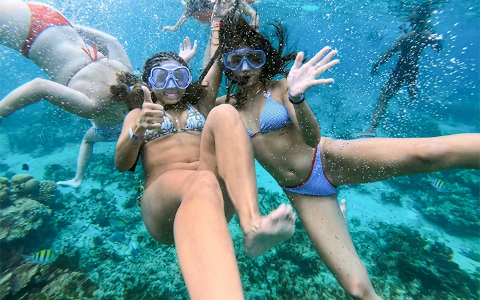 Snorkelers enjoying underwater view in Mansa Bay during private island day trip.