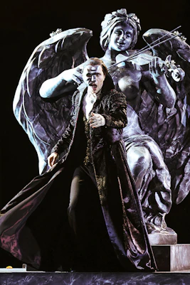 Performer in The Phantom of the Opera on Sydney Harbour with angel statue backdrop.