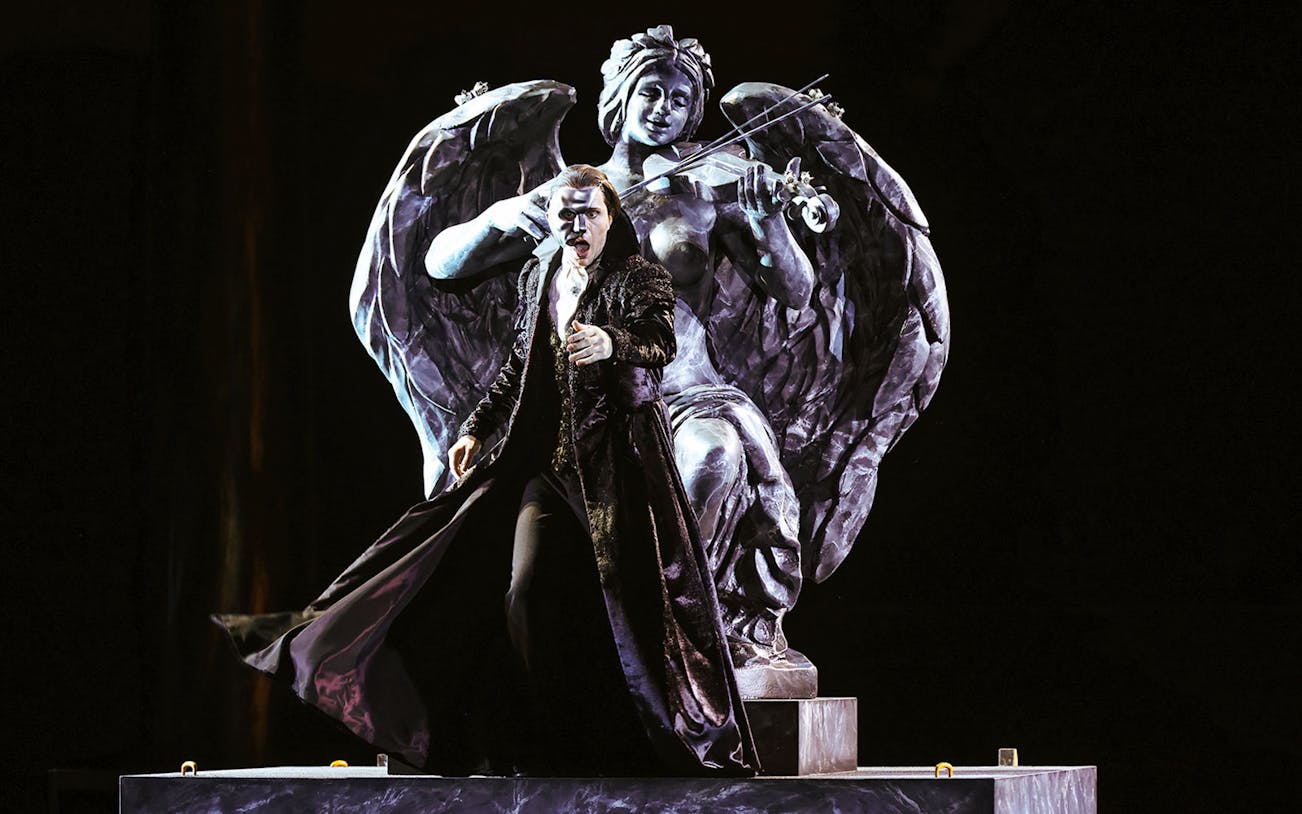 Performer in The Phantom of the Opera on Sydney Harbour with angel statue backdrop.