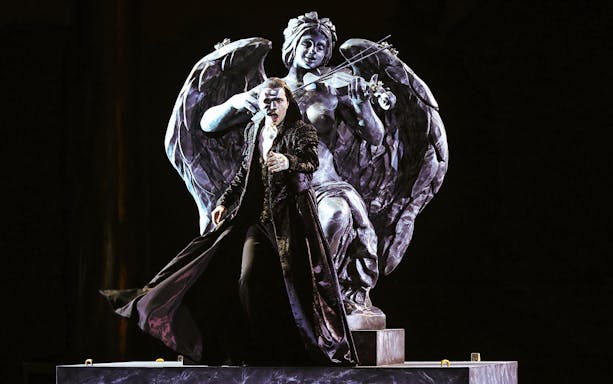 Performer in The Phantom of the Opera on Sydney Harbour with angel statue backdrop.