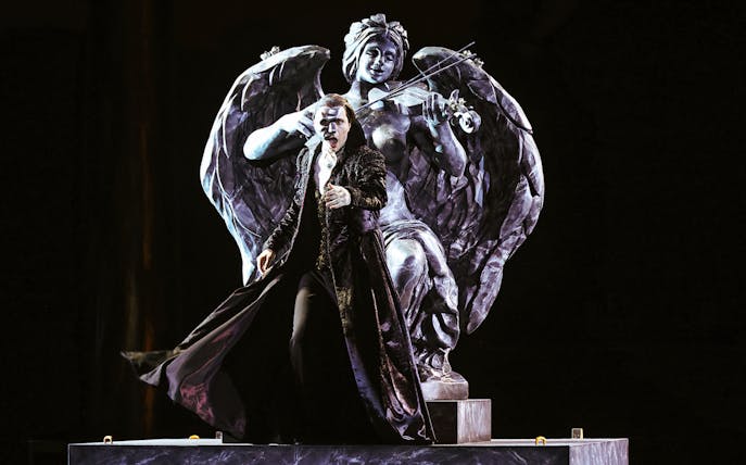 Performer in The Phantom of the Opera on Sydney Harbour with angel statue backdrop.