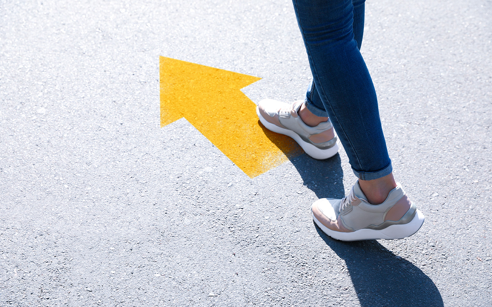 Person walking on pavement with yellow arrow, Las Golondrinas tour direction.