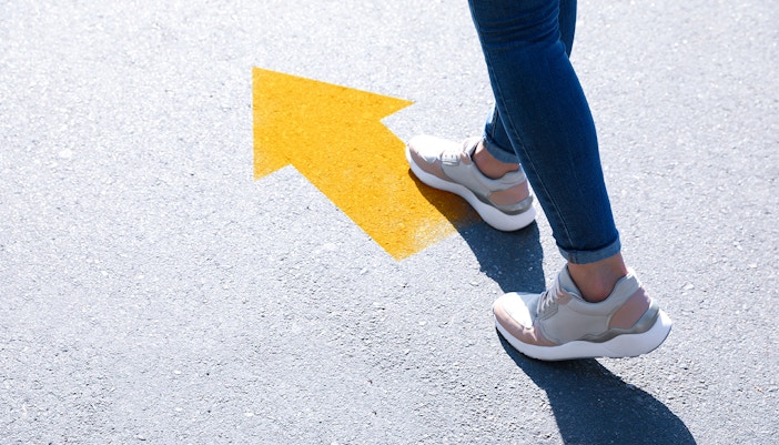 Person walking on pavement with yellow arrow, Las Golondrinas tour direction.