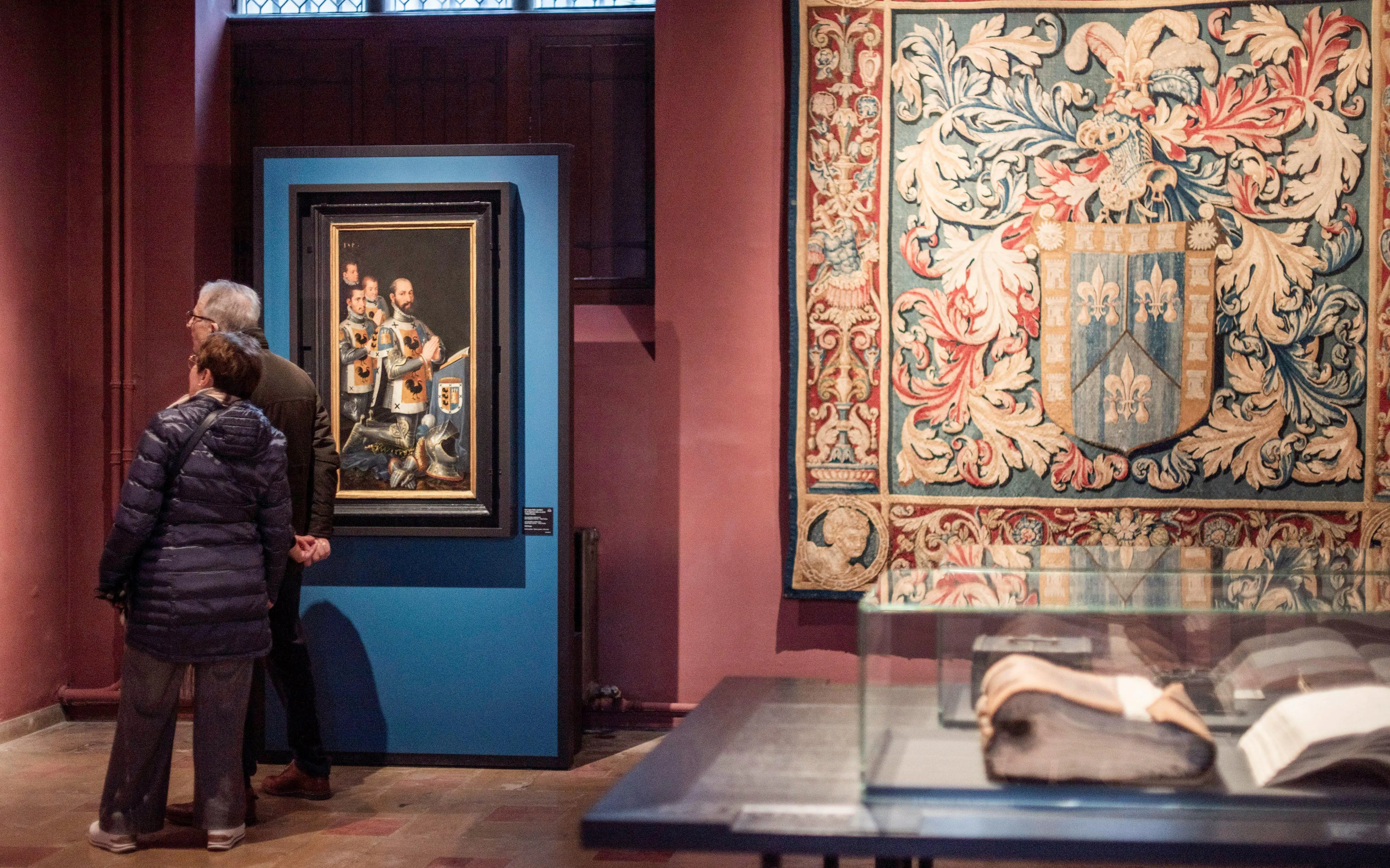 Visitors viewing artwork and tapestry at Gruuthusemuseum in Bruges.