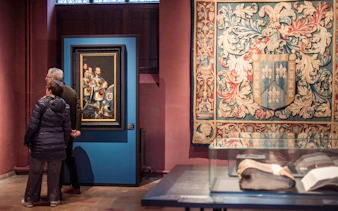 Visitors viewing artwork and tapestry at Gruuthusemuseum in Bruges.