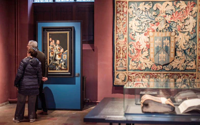 Visitors viewing artwork and tapestry at Gruuthusemuseum in Bruges.