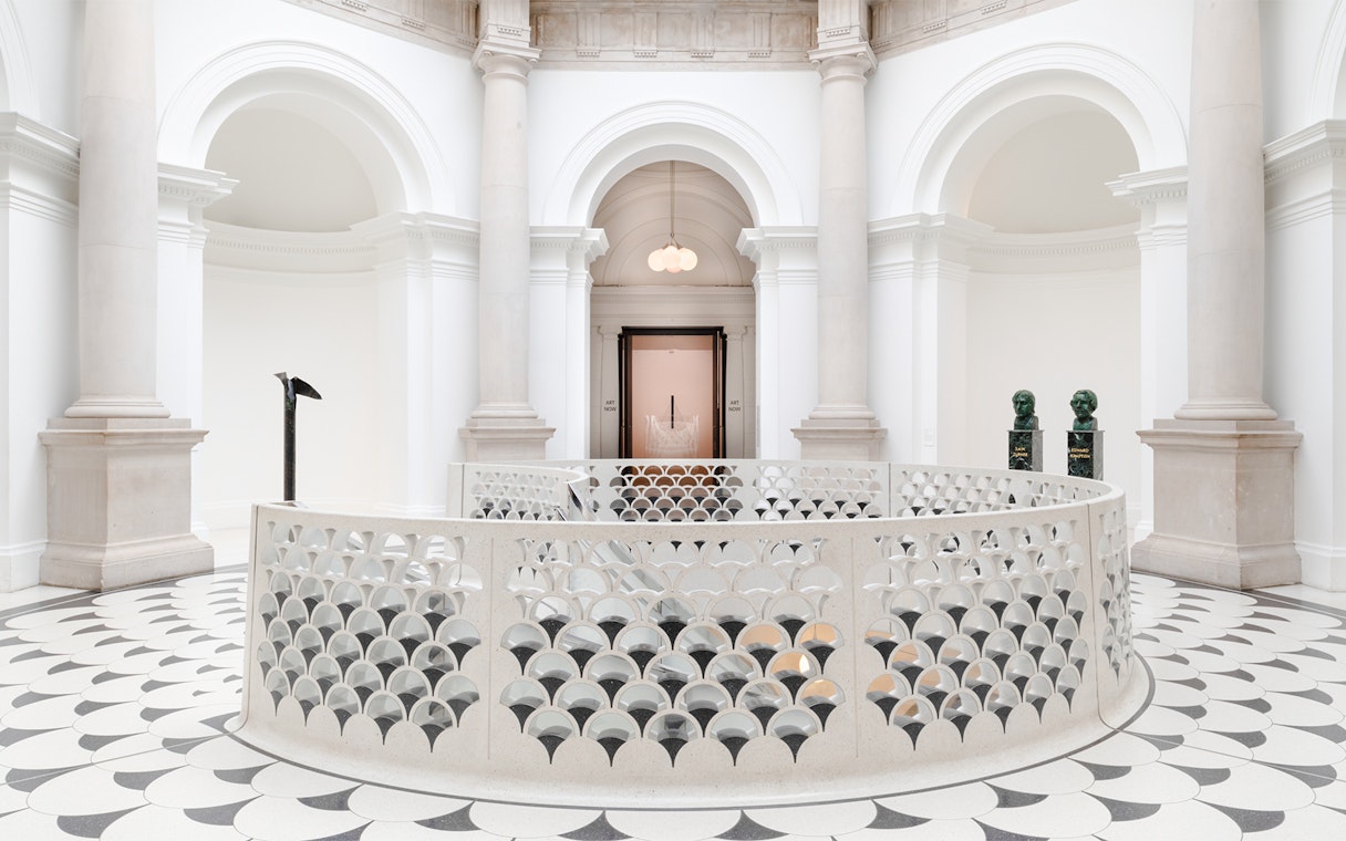 Tate Britain interior with ornate railing, columns, and sculptures in London.