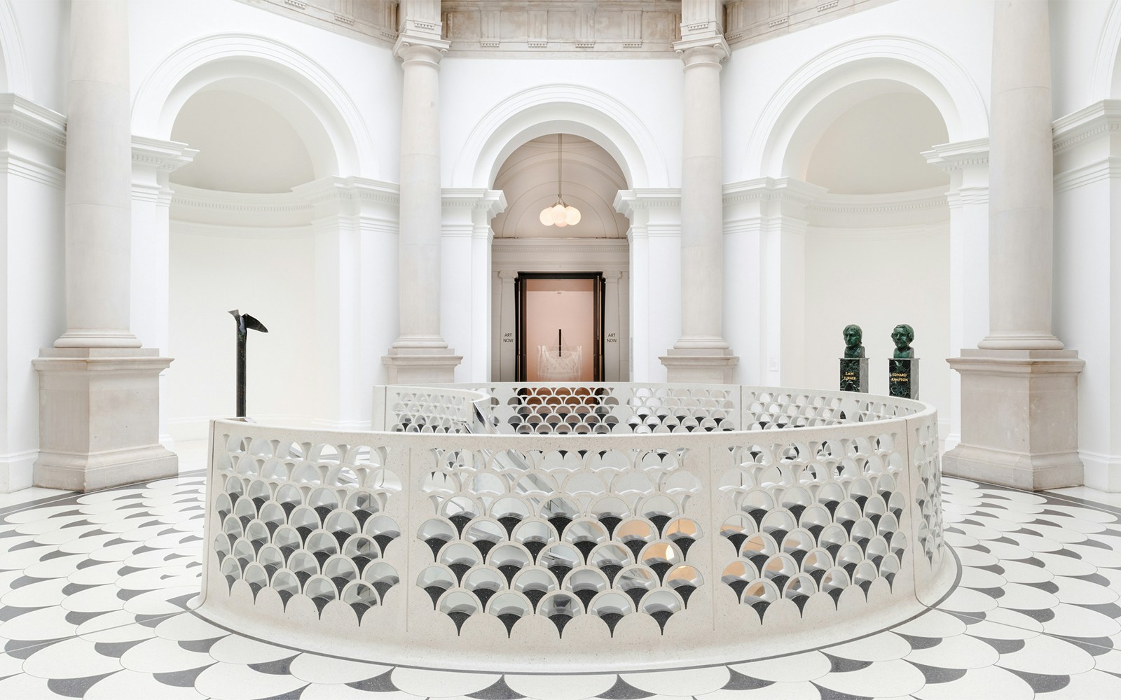 Tate Britain interior with ornate railing, columns, and sculptures in London.