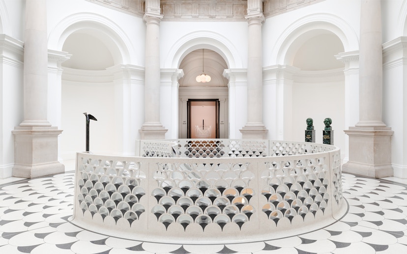 Tate Britain interior with ornate railing, columns, and sculptures in London.