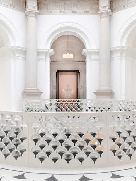 Tate Britain interior with ornate railing, columns, and sculptures in London.