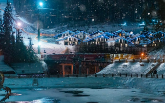 Ski resort in Zakopane with illuminated chalets and snowy slopes at night, Tatra Mountains.