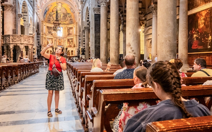 Guide explaining artwork to tourists inside Pisa Cathedral.