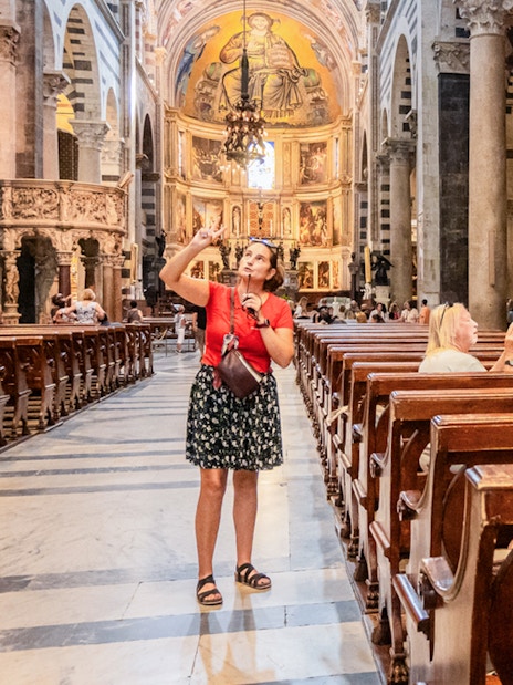 Guide explaining artwork to tourists inside Pisa Cathedral.