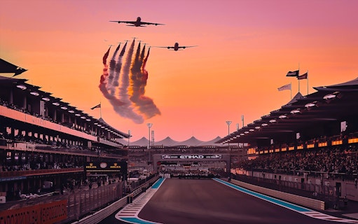 Airplanes flying over Yas Marina Circuit at sunset during Abu Dhabi Grand Prix.