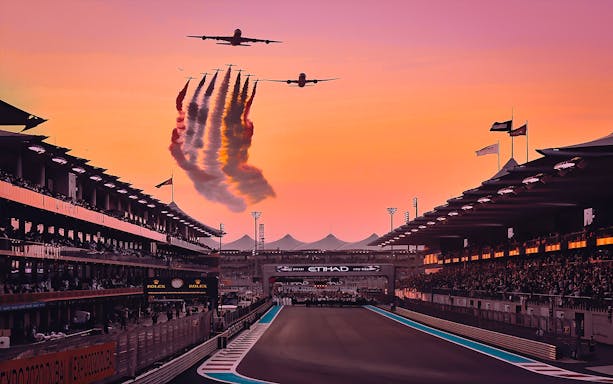 Airplanes flying over Yas Marina Circuit at sunset during Abu Dhabi Grand Prix.
