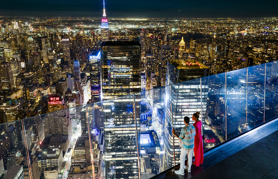 Couple enjoying night view of New York City skyline from Edge Observation Deck.