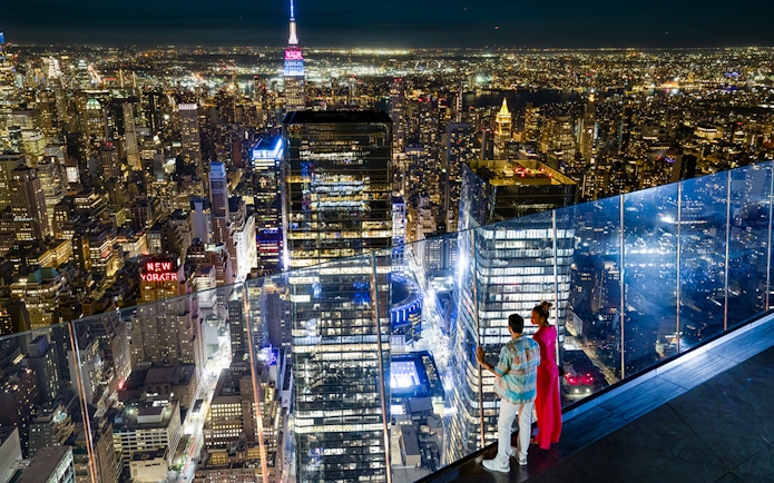 Couple enjoying night view of New York City skyline from Edge Observation Deck.
