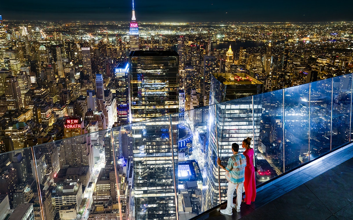 Couple enjoying night view of New York City skyline from Edge Observation Deck.