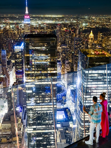 Couple enjoying night view of New York City skyline from Edge Observation Deck.