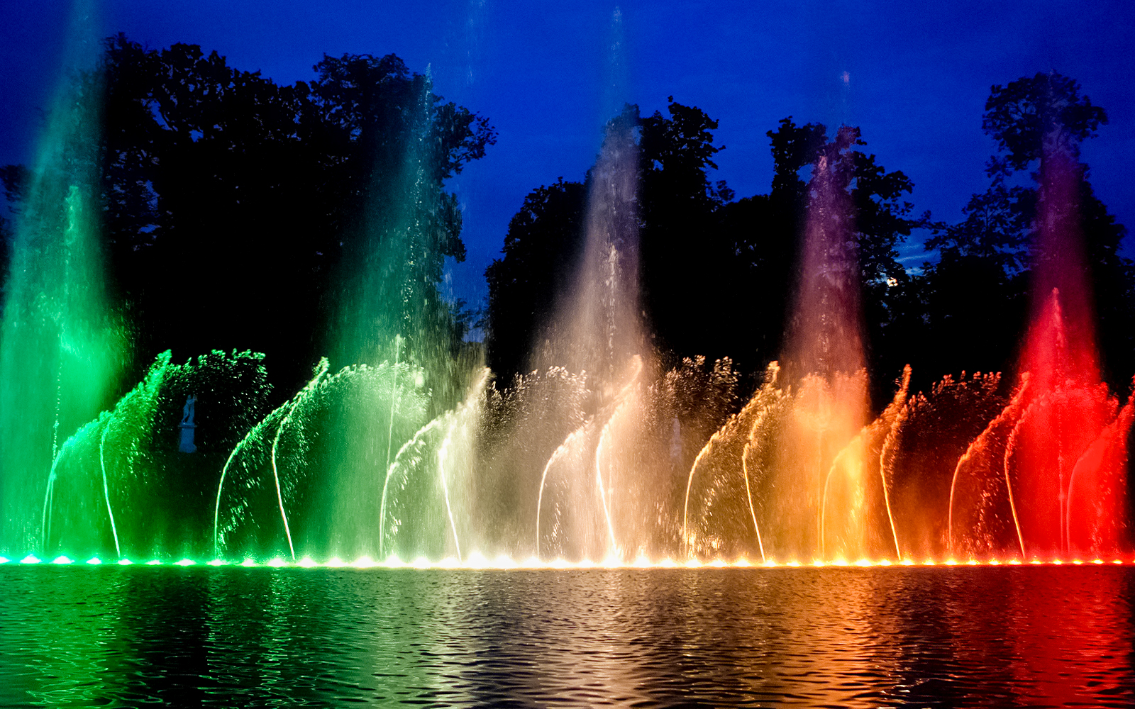 Fountains illuminated in vibrant colors at the Palace of Versailles show.