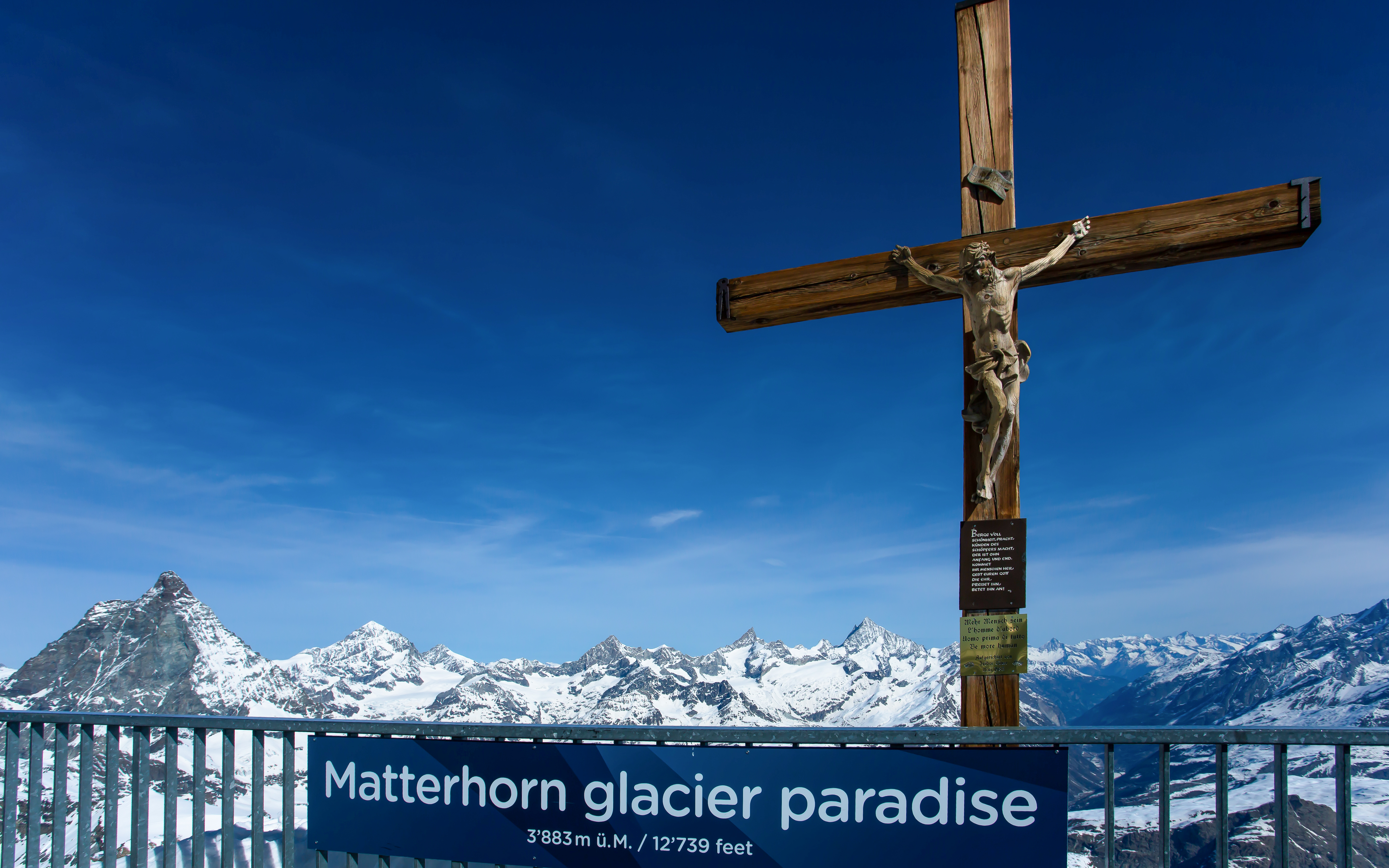 Viewing platform at Matterhorn Glacier Paradise with cross and snowy mountain peaks.