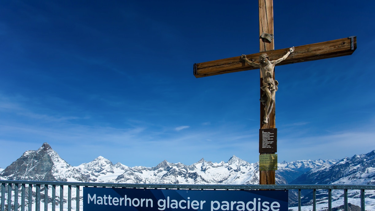 Viewing platform at Matterhorn Glacier Paradise with cross and snowy mountain peaks.