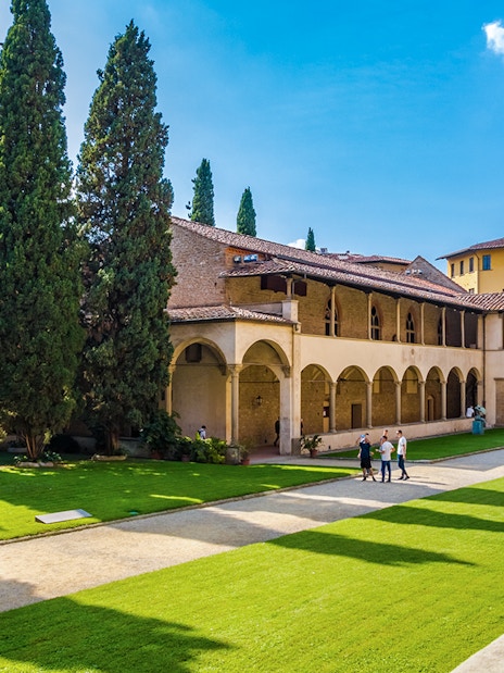 Cloisters of Santa Croce Basilica Complex with statue and visitors in Florence, Italy.