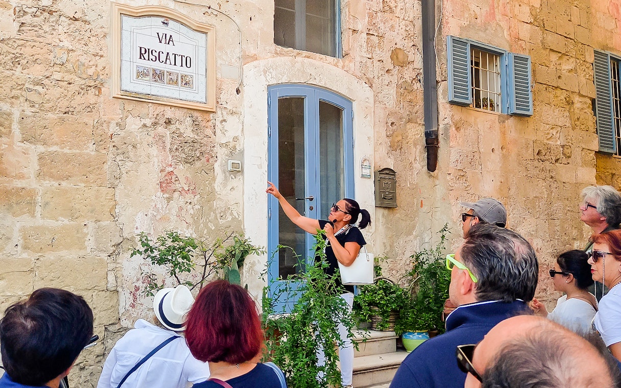 Tour guide with audio device explaining historical site to group on bus tour.