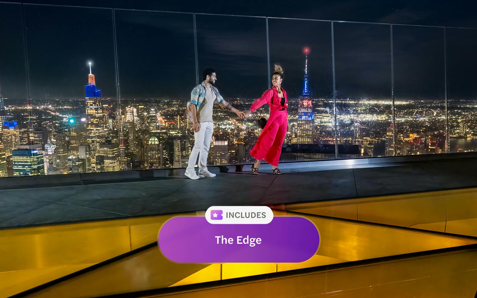 Couple enjoying night view from Edge Observation Deck, New York City skyline in background.